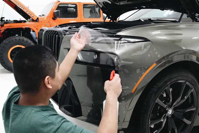 Paint protection film being applied to a BMW X7 front end at FRQNCY